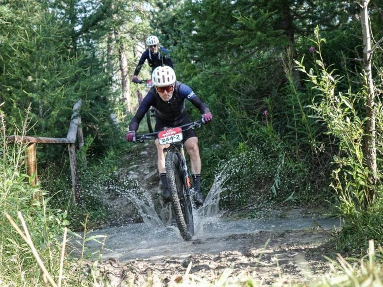 biking through a mountain path with a river that bikers are traversing