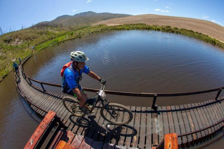 Biker on a narrow bridge over a river