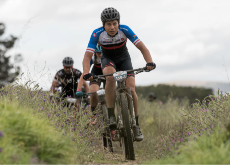 Three bikers heading down a grassy area