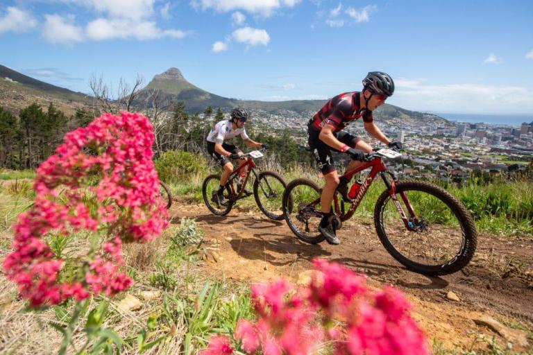 Three bikers on a path with pink flowers