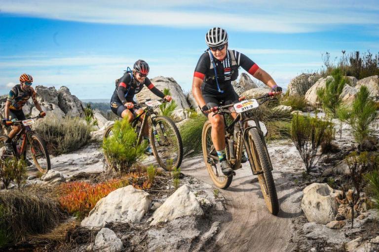 Kylie Burrows leading three bikers around a curve in the mountains