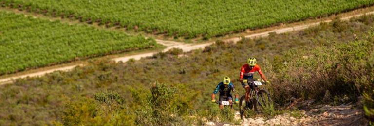 Becking and Dias cycling up a field 