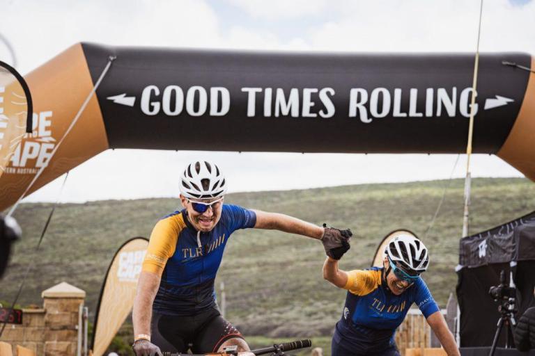Two bikers crossing the cape to cape finish line with the words good times rolling 