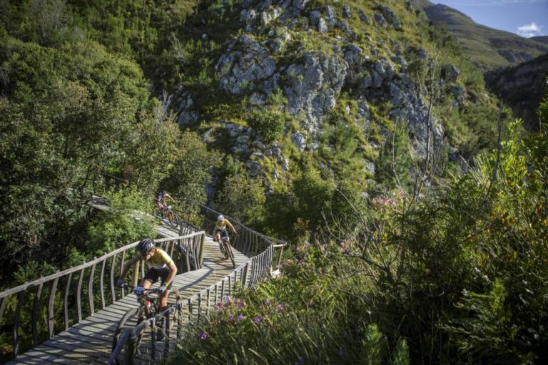 Three bikers on a narrow wooden path/bridge
