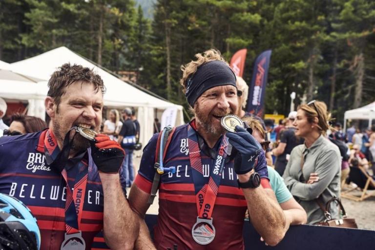 Two bikers biting their Swiss Epic 2019 medals
