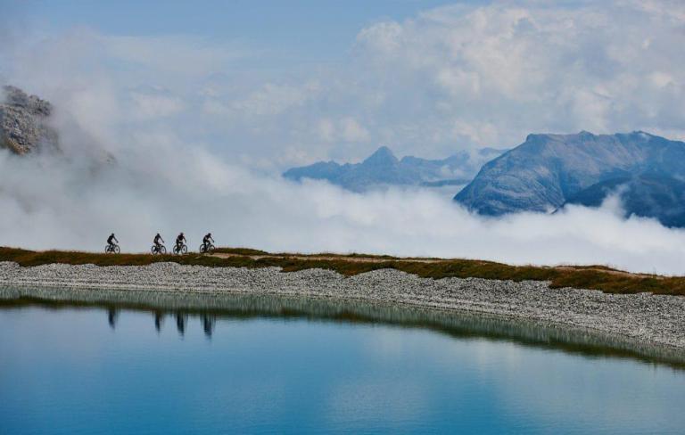 Four Bikers heading on the swiss epic with fog in the background