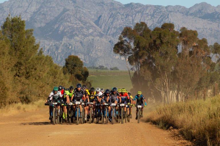 A whole cloud of bikers with a large mountain in the background