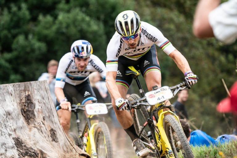 Schurter and Forster racing past a stump