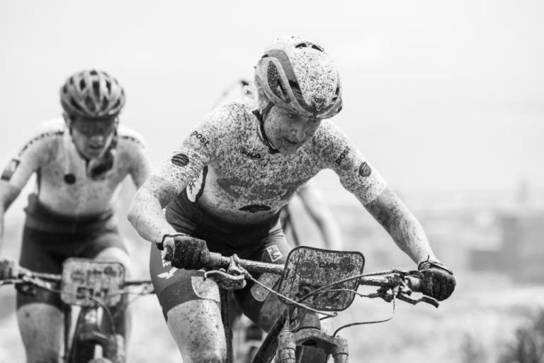 Black and white image of bikers covered in mud