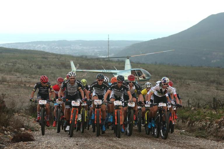 Bikers heading up a hill with a helicopter in the background