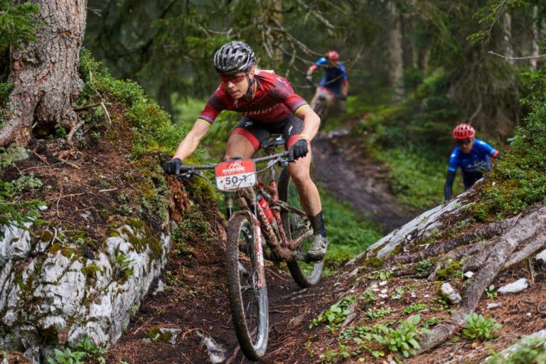 Three bikers on a narrow path through the woods