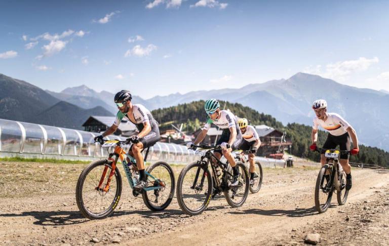 Four bikers heading across a dirt road
