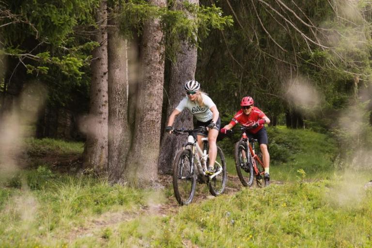 Ariella Kaeslin biking through a forest with her partner