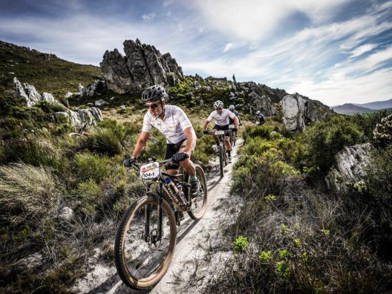 dramatic action shot of four bikeres heading down a narrow path