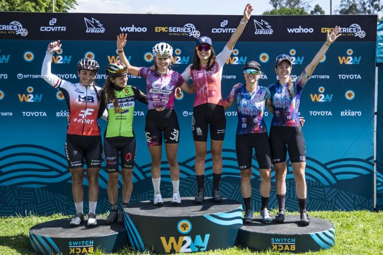 Elite women’s podium after Stage 1 of the 2025 FNB Wines2Whales Chardonnay (from left to right): Margot Moschetti, Claudia Peretti, Tyler Jacobs, Candice Lill, Robyn de Groot, and Sarah Hill. Photo by Dom Barnardt. 