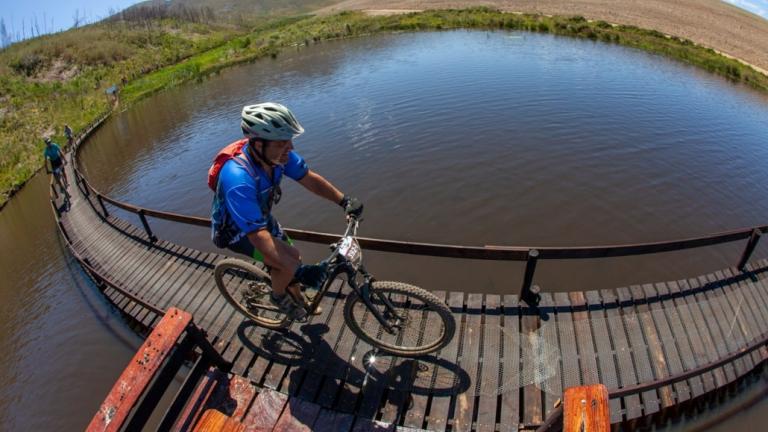A biker heading over a narrow bridge [FNB Wines2Whales]
