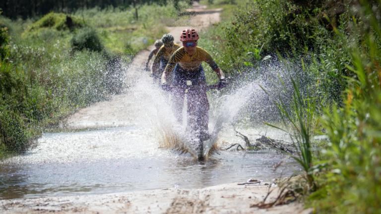 Adelheid Morath, from team Faces, splashes through one of the puddles left on the route after the previous day’s downpour. Image by Xavier Briel [FNB Wines2Whales]