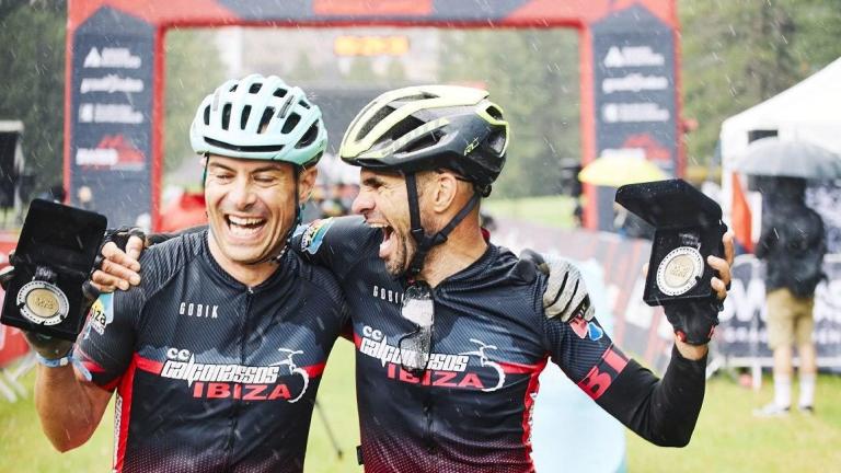 Two bikers in the rain showing off their 2020 Swiss Epic Medals [Swiss Epic]