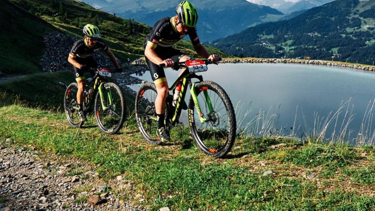 Two bikers heading along a lakeside path [cape epic]