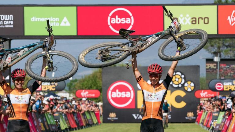 Annika Langvad and partner holding their bikes over their head [Swiss Epic]