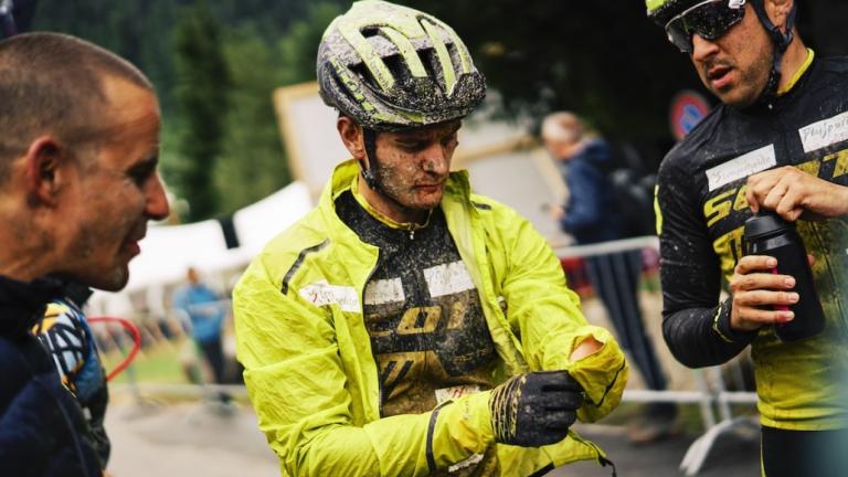 A biker covered in mud adjusting his sleeve [Swiss Epic]