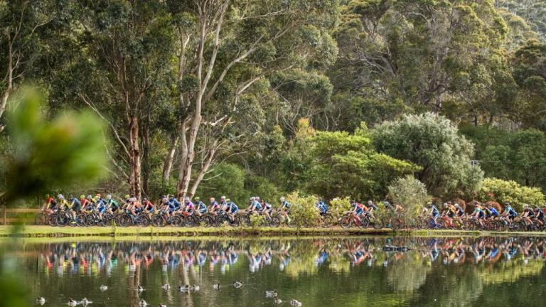 Hundreds of bikers heading across a path near a lake [Cape to Cape]