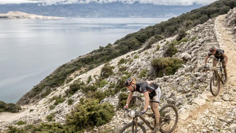 Two bikers on a mountain path with a lake in the background [Epic Series]