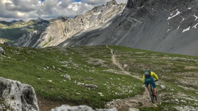 Stefan Wolfisberg biking through a valley [Swiss Epic]
