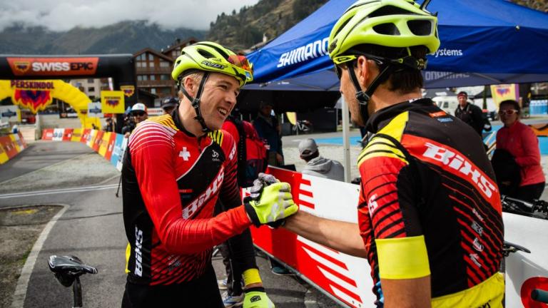 Two bikers grasping hands [Swiss Epic]