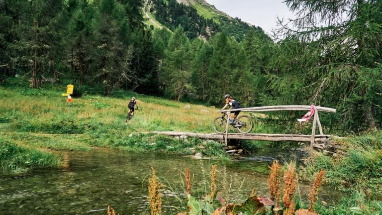 Two bikers heading over a bridge on the Graubunden race [Swiss Epic]