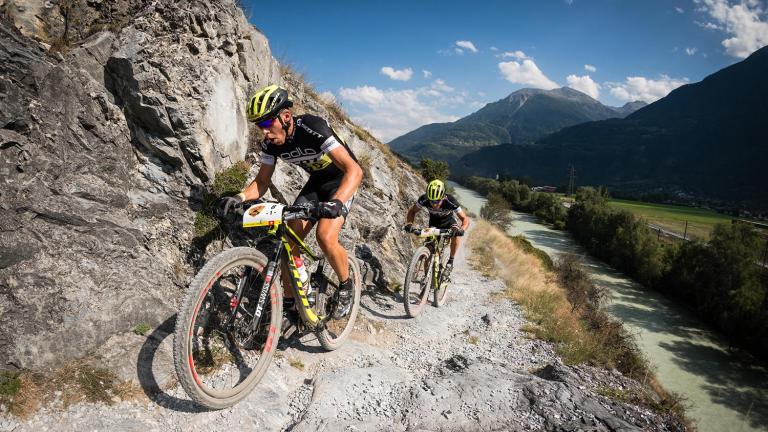 Two bikers biking up the side of a mountain [Swiss Epic]