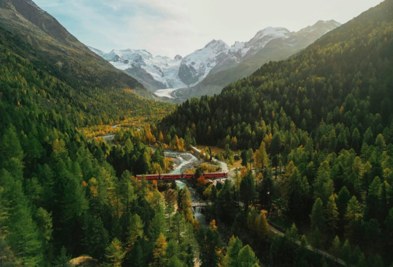 Bird's eye view of the nature in Graubünden with a city in between forests and mountains