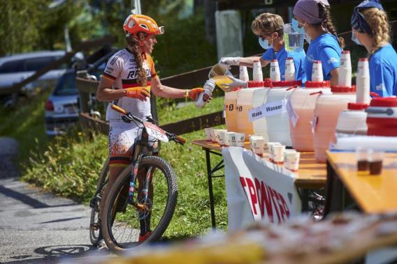 Rider at an aid station refilling the drink bottle at Swiss Epic