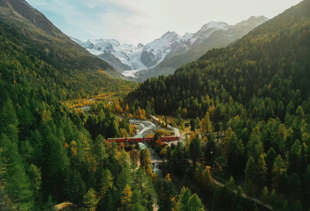Bird's eye view of the nature in Graubünden with a city in between forests and mountains