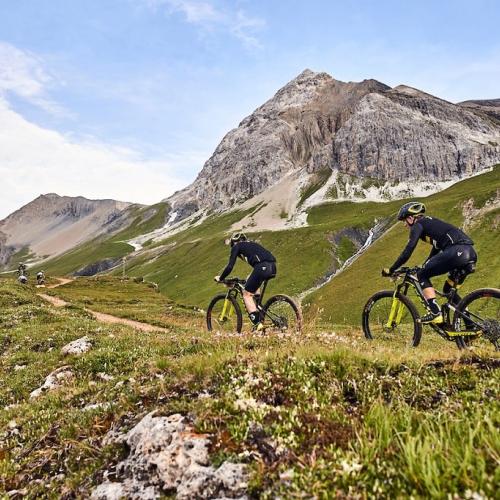 Two bikers biking against the hills of Graubünden  [Swiss Epic]