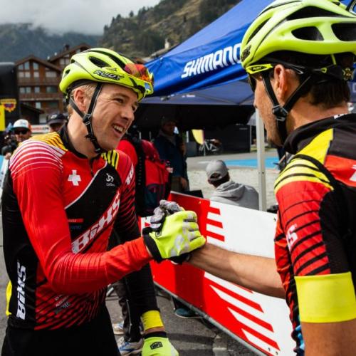 Two bikers grasping hands [Swiss Epic]