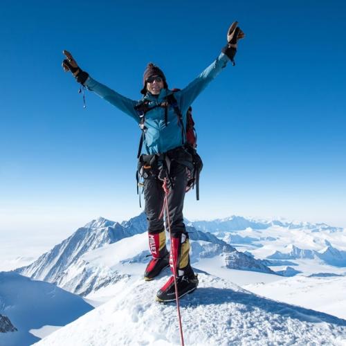 Wayne Morris with his arms outstretched on a mountain peak [Swiss Epic]