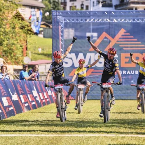 Four bikers crossing the swiss epic line with fists in the air [Swiss Epic]